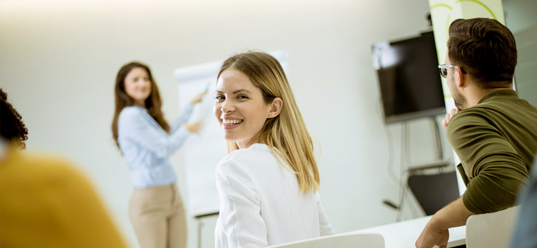 Participant souriante lors d'une session de formation en salle avec tableau blanc, illustrant les formations CSE obligatoires pour les élus du comité