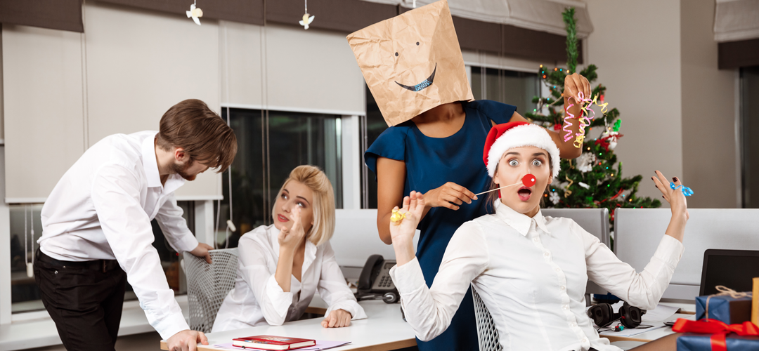 Collègues célébrant Noël au bureau avec des cartes cadeaux, accessoires festifs et sapin de Noël en arrière-plan